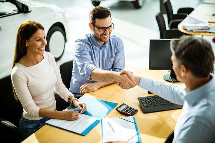 Successful deal in a car showroom! Happy couple leasing a car