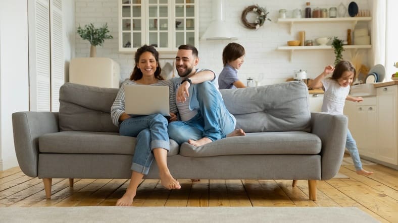 Parents on computer with kids in back Family looking up cars on laptop